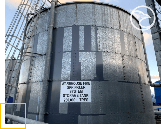 A large industrial water storage tank for a fire sprinkler system with a capacity of 260,000 liters, situated outdoors under a cloudy sky.